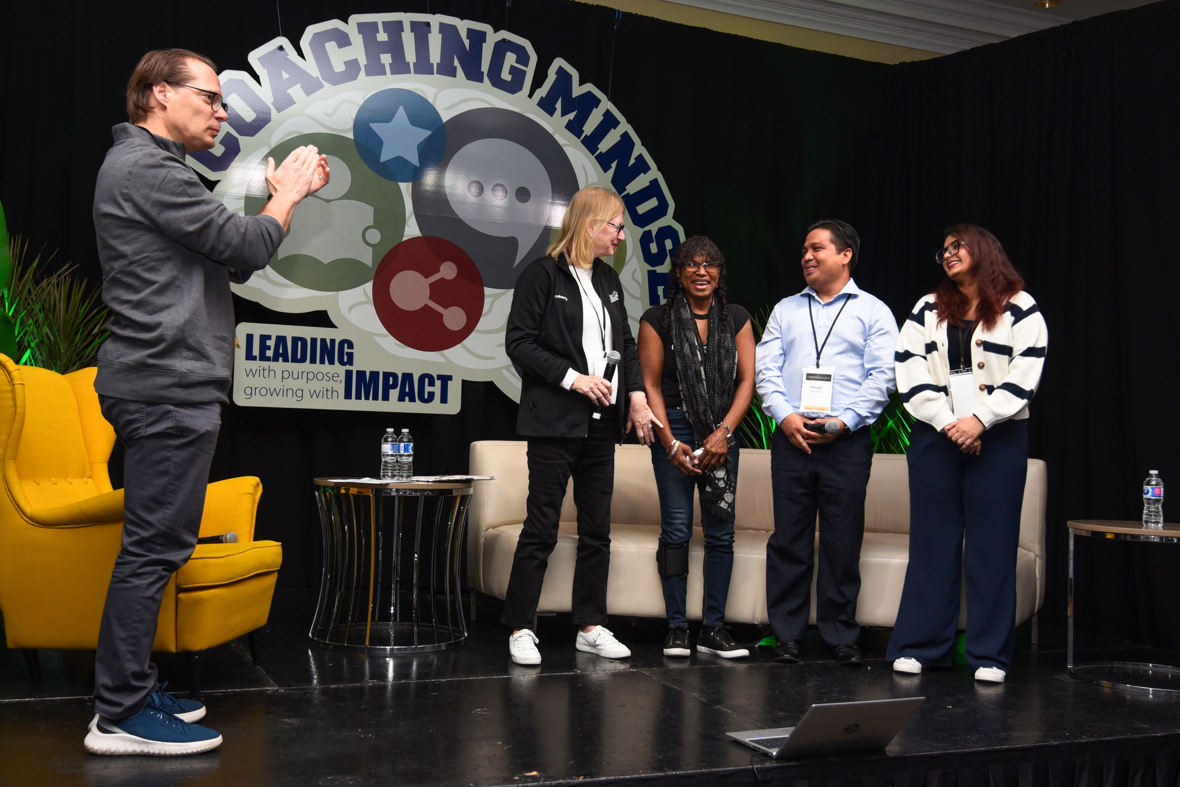 Jamie Schlegel stands upon the stage at the annual leadership retreat and applauds the four panelists, Kim, Hilda, Vergel and Jashan.